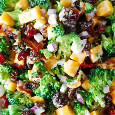 Broccoli salad with bacon, raisins, and cheddar cheese served in a bowl
