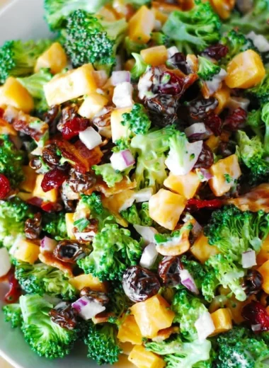 Broccoli salad with bacon, raisins, and cheddar cheese served in a bowl