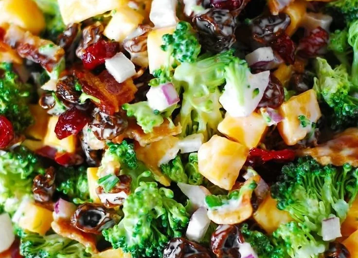 Broccoli salad with bacon, raisins, and cheddar cheese served in a bowl