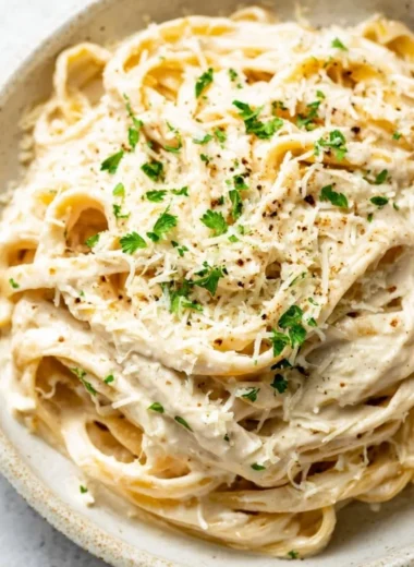 Bowl of creamy homemade Alfredo Sauce with garnished parsley.