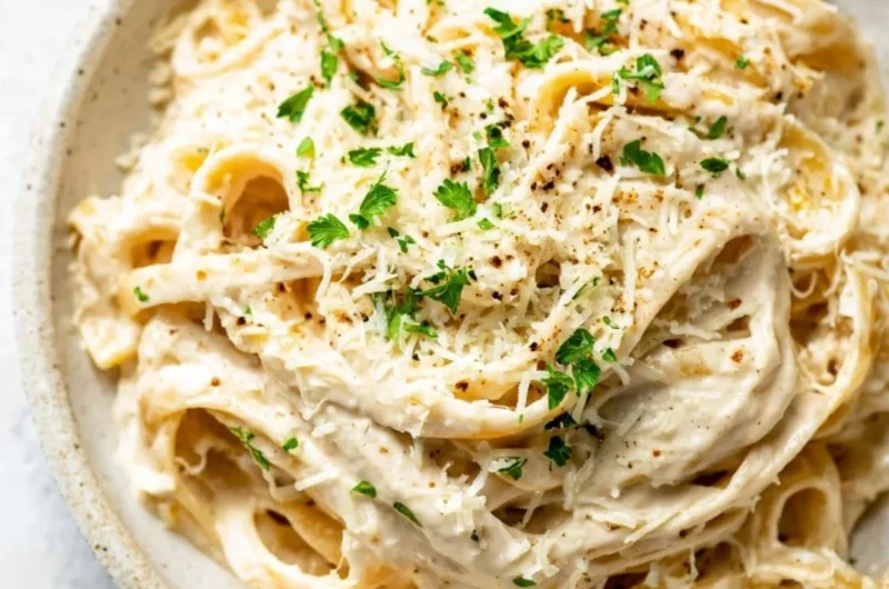 Bowl of creamy homemade Alfredo Sauce with garnished parsley.