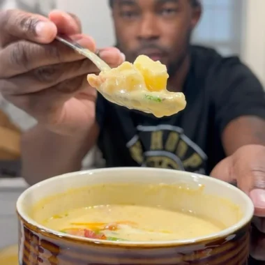 Bowl of creamy loaded potato soup topped with cheese and green onions