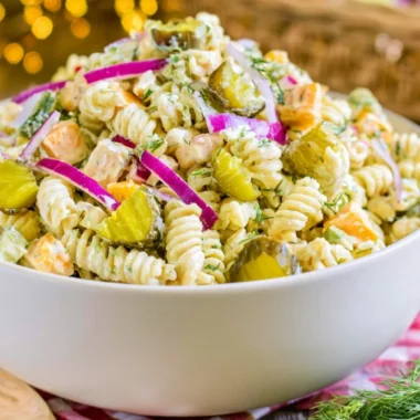 Creamy dill pickle macaroni salad in a serving bowl with fresh herbs