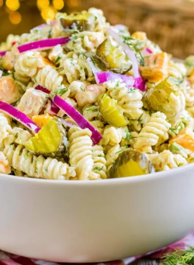 Creamy dill pickle macaroni salad in a serving bowl with fresh herbs