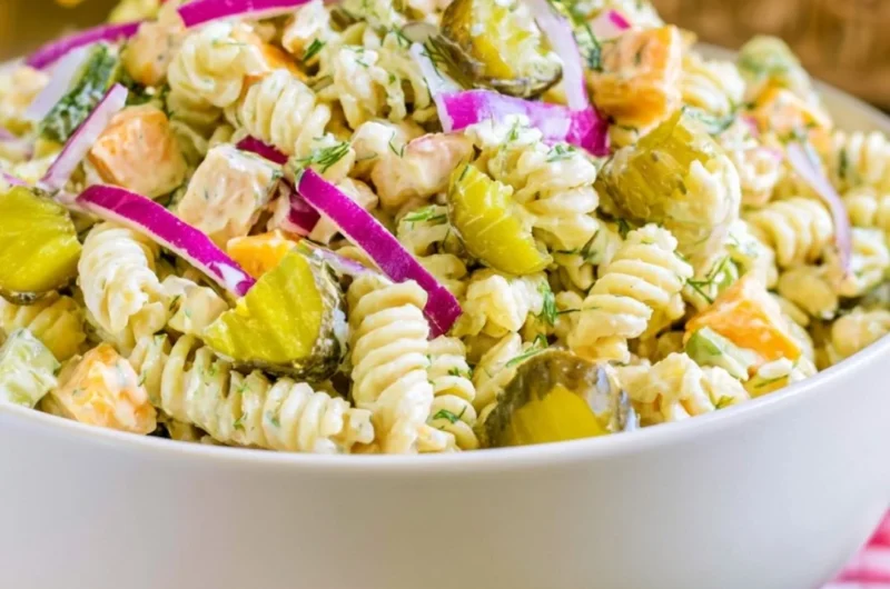 Creamy dill pickle macaroni salad in a serving bowl with fresh herbs