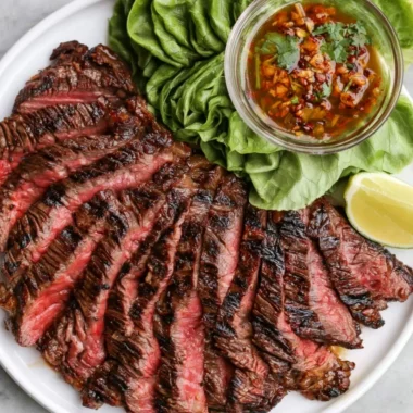 Plate of Crying Tiger Beef garnished with herbs and served with dipping sauce