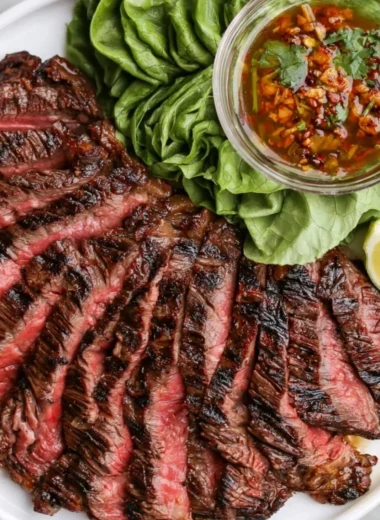 Plate of Crying Tiger Beef garnished with herbs and served with dipping sauce