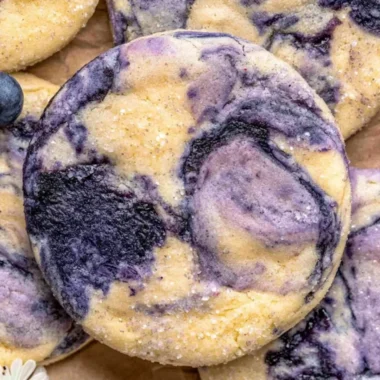 Lemon Blueberry Cheesecake Cookies on a plate with a bright lemon background.