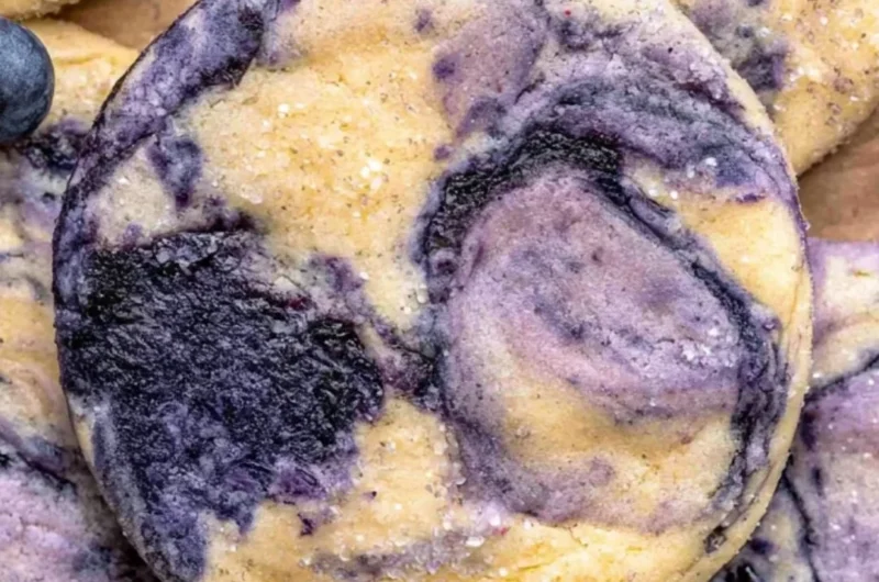 Lemon Blueberry Cheesecake Cookies on a plate with a bright lemon background.