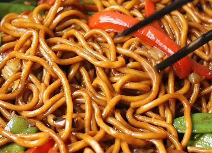 A bowl of Lo Mein noodles topped with colorful vegetables and savory sauce.