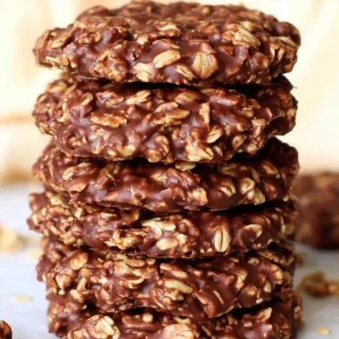 No bake chocolate oatmeal cookies on a plate, topped with chocolate drizzle.