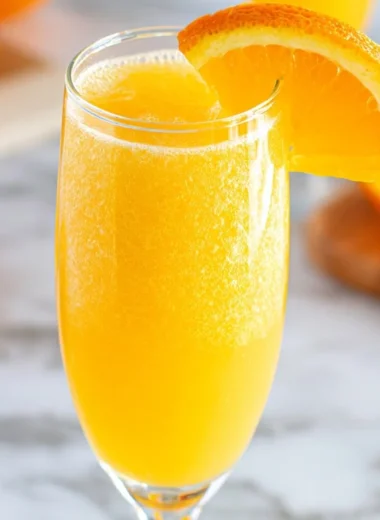 Freshly made non-alcoholic mimosa served in a glass with orange slices.
