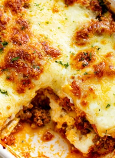 Cozy Easy Lasagna topped with melted cheese and fresh herbs on a baking dish.