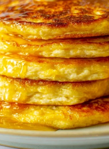 Cozy orange ricotta pancakes served on a plate, drizzled with syrup.