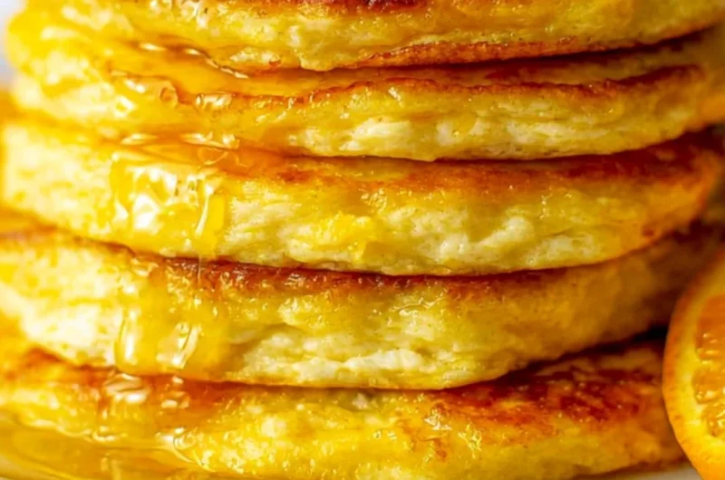 Cozy orange ricotta pancakes served on a plate, drizzled with syrup.