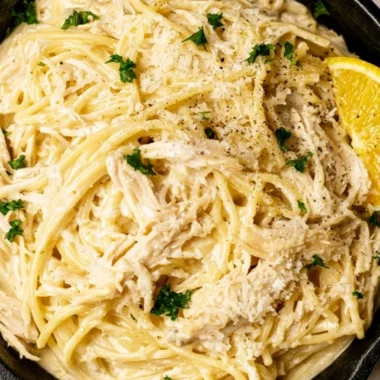 Creamy lemon chicken pasta served on a plate with fresh herbs and lemon slices
