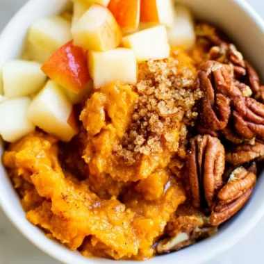 Sweet potato breakfast bowl topped with pecans and apples, a nutritious start to the day.